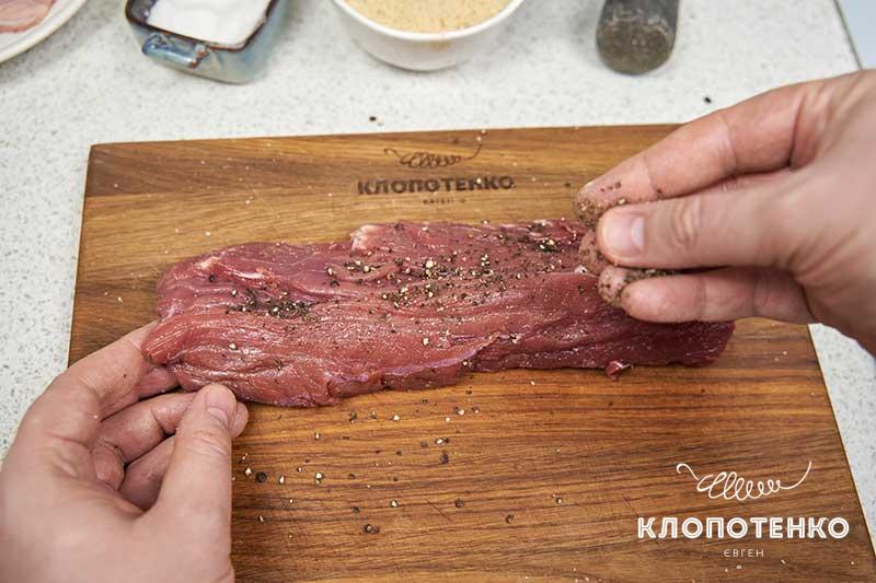 Обильно присыпьте мясо перцем и солью