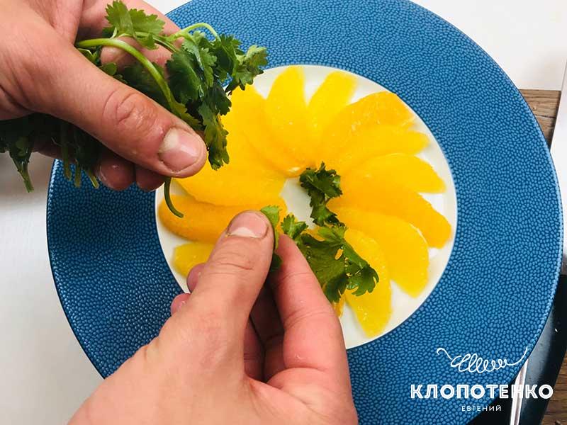 На апельсин выложите промытые листики кинзы