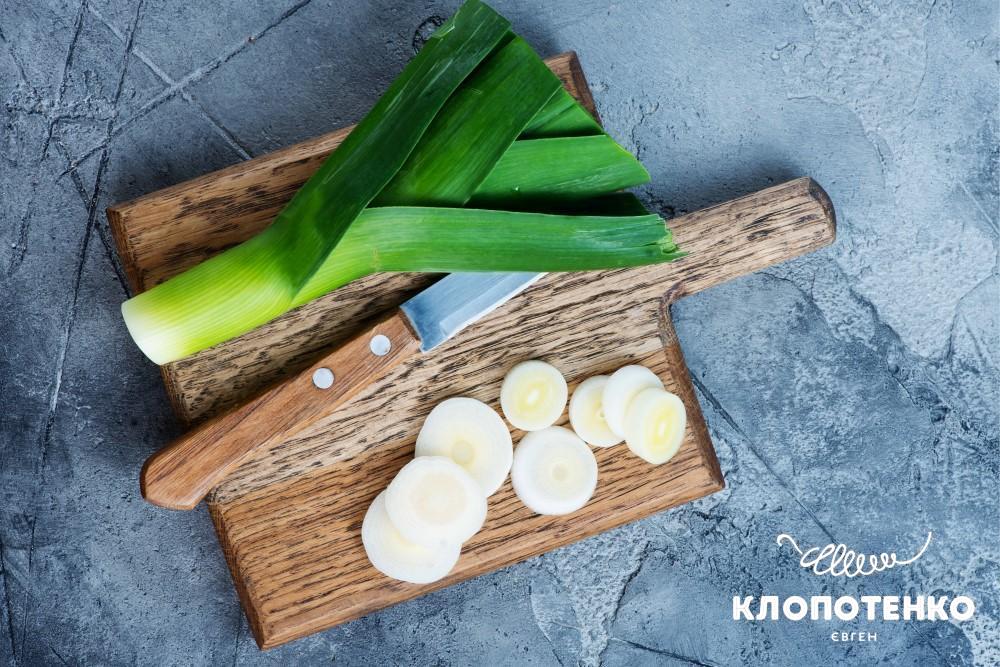 Цибуля порей на дошці, чим корисна цибуля порей та що готувати з нею