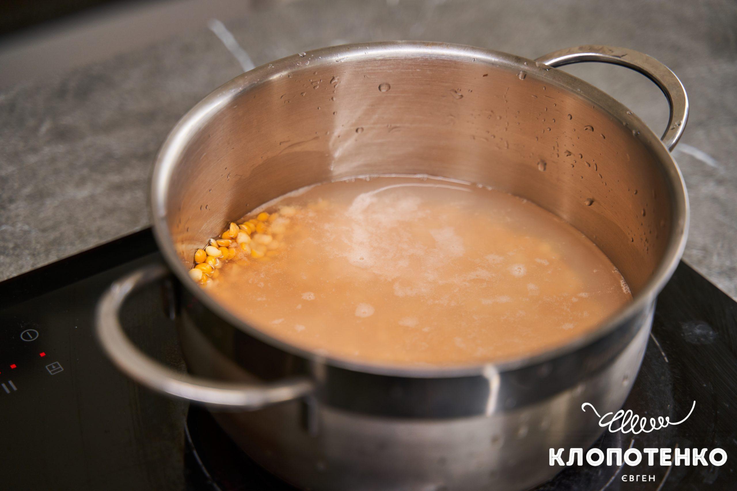 Сирий горох залитий водою у каструлі