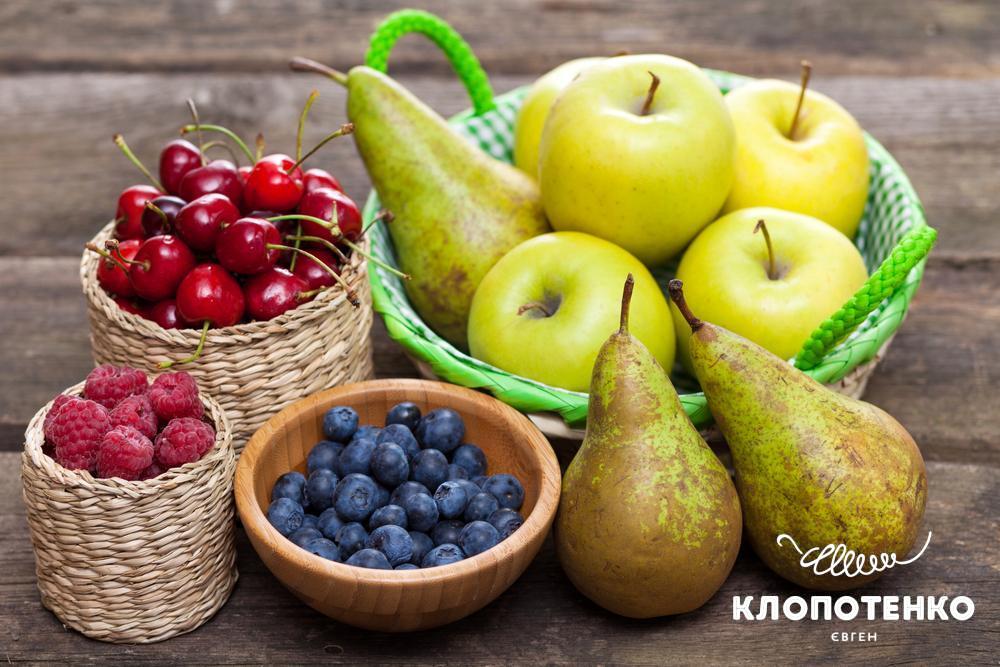 Яблука, груші та ягоди красиво лежать на столі