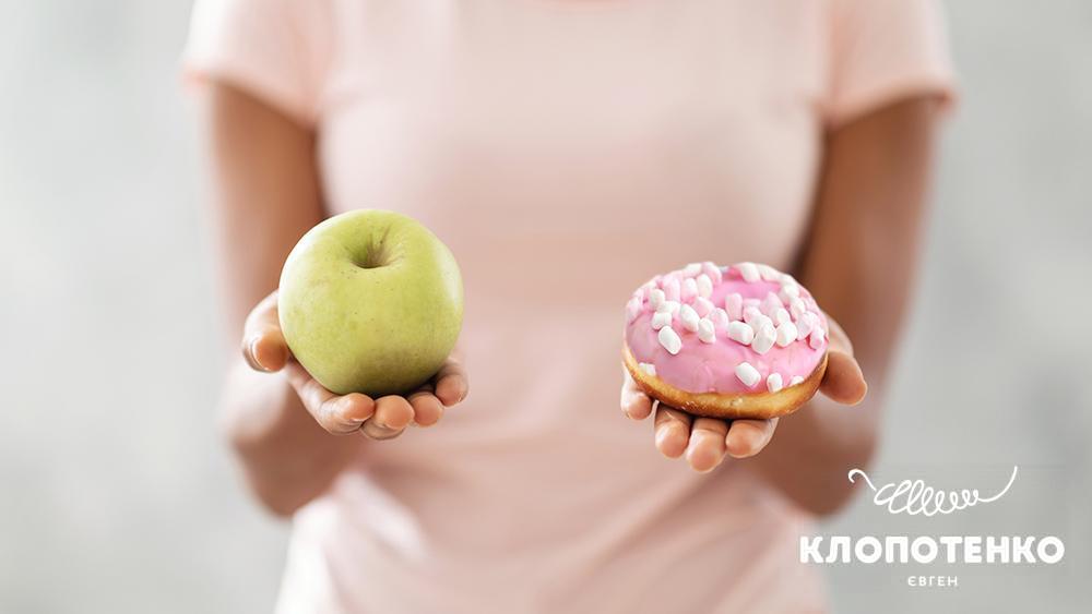 Людина тримаю яблуко в одній руці та печиво в іншій