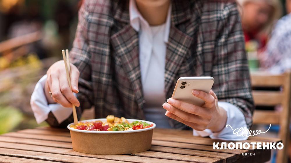 Людина тримає телефон і їсть