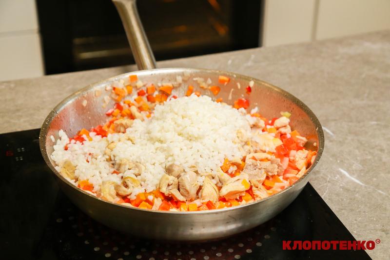 Додавання рису на пательню до курки та овочів