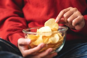 людина їсть чіпси зі скляної посуди